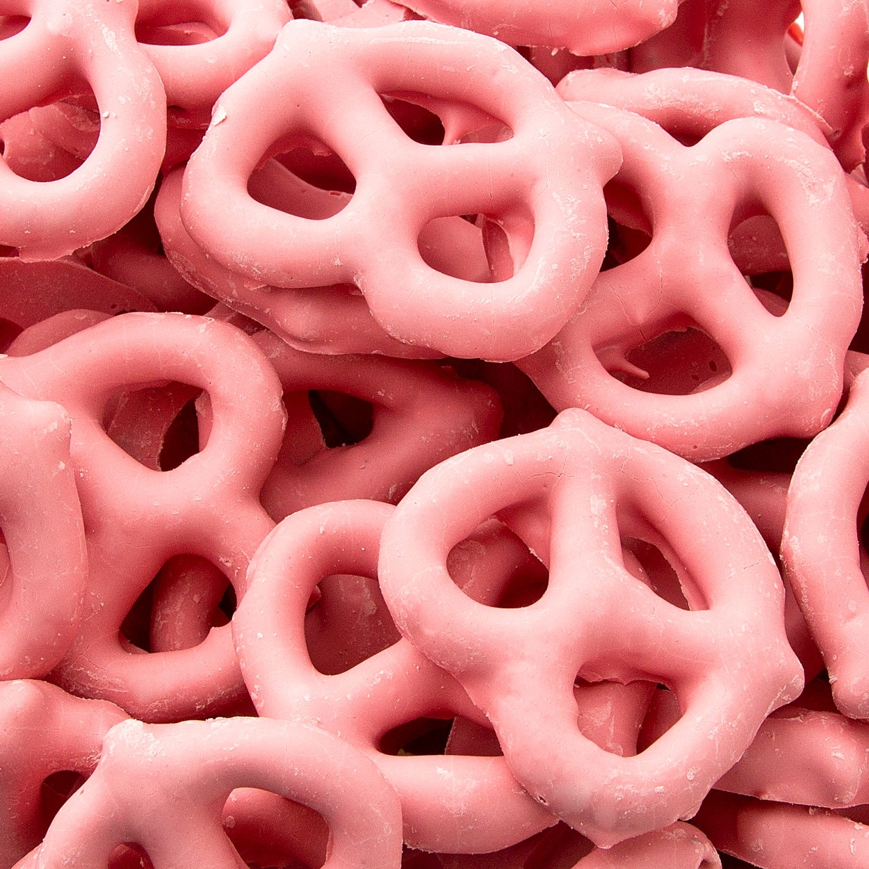 Pile of pink yogurt-covered pretzels with smooth coating and traditional pretzel knot shape