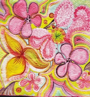 Colorful quilted fabric with large pink and yellow stylized flowers and swirling green patterns