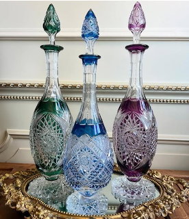 Three colored cut crystal decanters with stoppers on an ornate gold tray