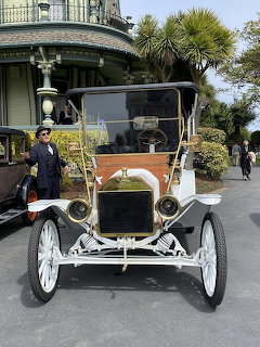 Orange and black 1911 Ford Model T vintage car with white wheels on display outdoors