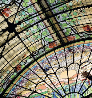 Art Nouveau stained glass ceiling with floral patterns and black iron framework in geometric design