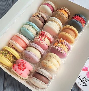 White gift box filled with assorted colorful French macarons arranged in neat rows