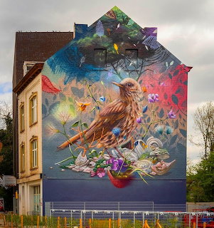 Colorful street art mural of bird with tropical flowers on building wall
