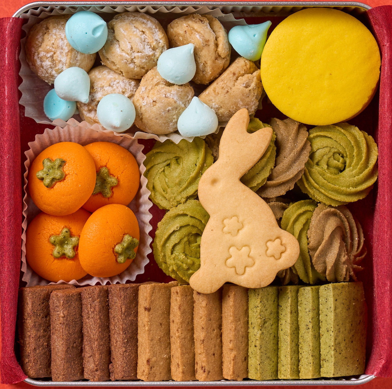 Square box of assorted cookies, meringues, biscuits, and small oranges