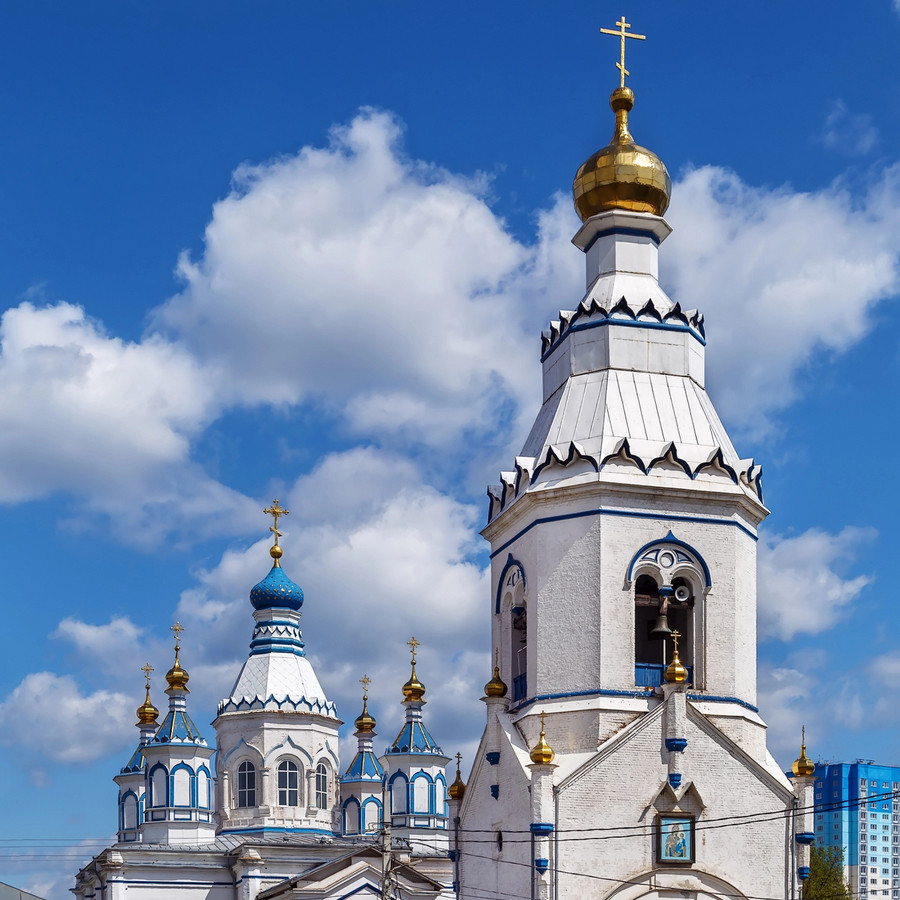 White Orthodox monastery with golden domes and bell tower against blue sky in Tula, Russia