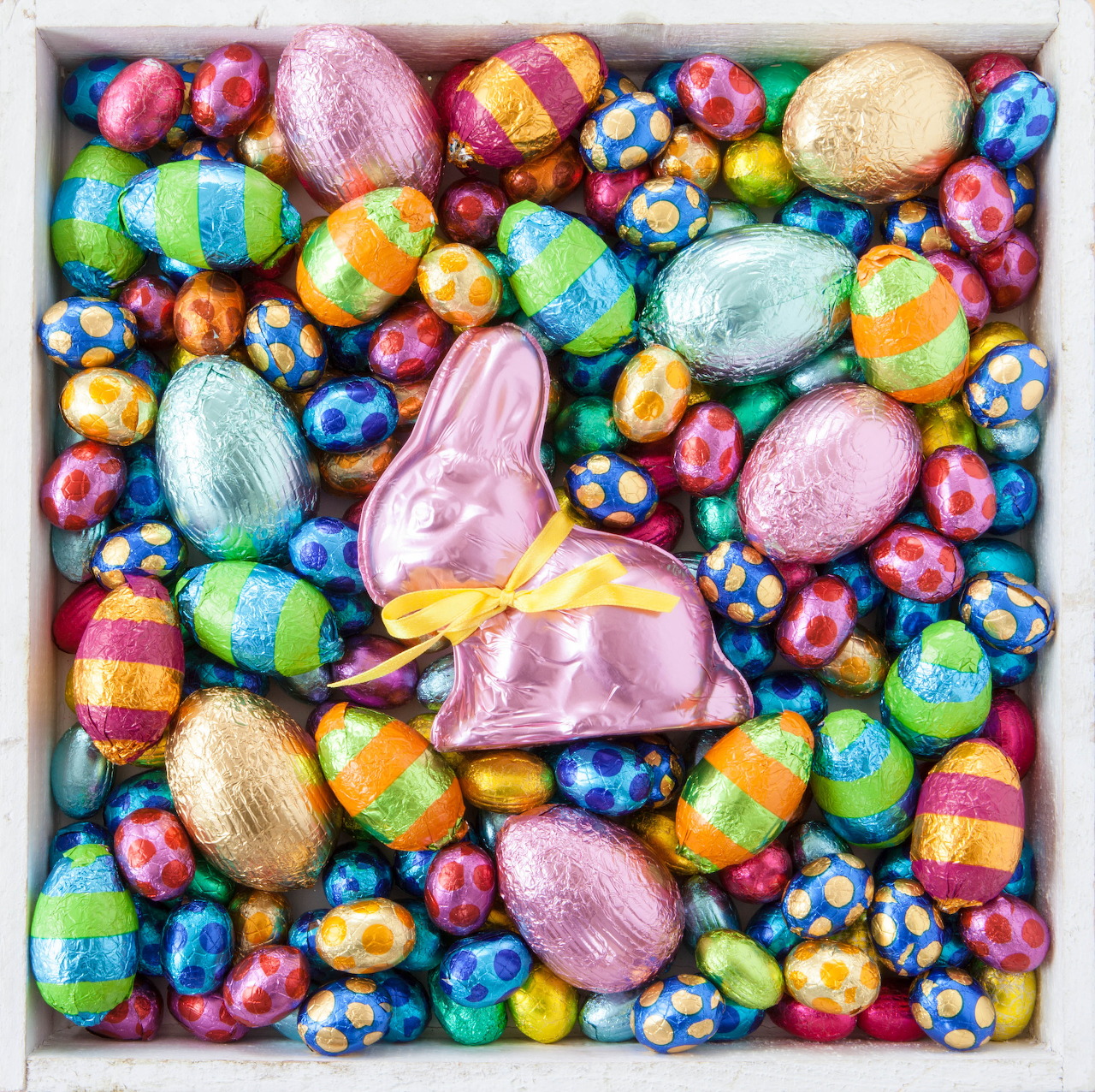 Assorted foil-wrapped Easter chocolate eggs and pink bunny in white box