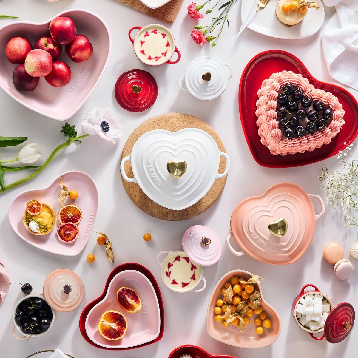 Overhead Valentine's table with heart-shaped plates, cake, tea, fruit, and pink desserts