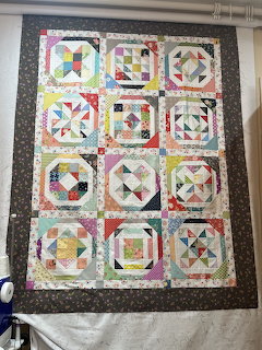 Colorful patchwork quilt with geometric blocks in a grid pattern on dark border