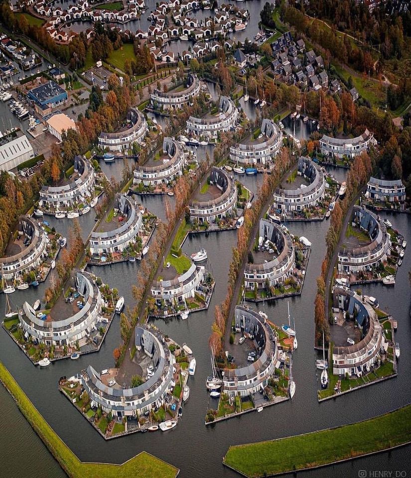 Aerial photograph of circular residential buildings arranged in curved rows with trees and streets between them