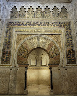 Ornate golden mihrab prayer niche with horseshoe arch and geometric Islamic patterns in Córdoba mosque
