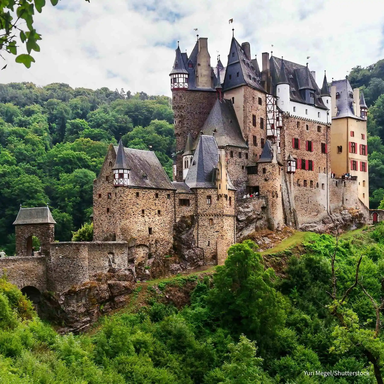 Medieval castle with multiple towers on forested hillside