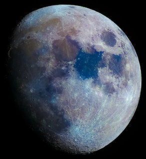 Detailed moon photograph showing craters and blue-gray surface features against black background