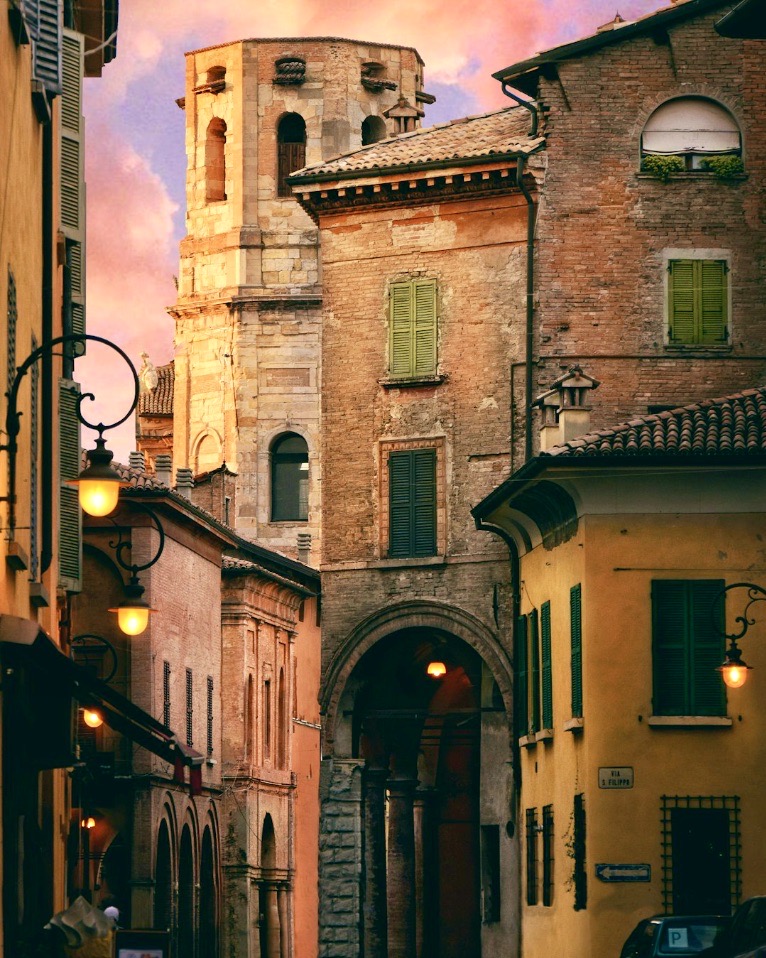 Historic narrow street in Reggio Emilia, Italy with old buildings, archway, and tower