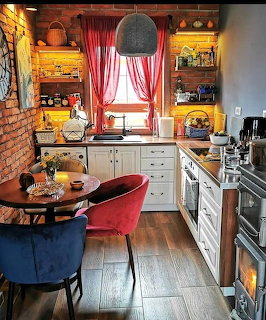 Colorful eclectic kitchen with blue and red chairs, white cabinets, red curtains, exposed brick wall, and yellow shelving