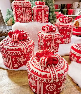 Red and white Christmas ornament shaped cakes with decorative icing patterns on wooden table with holiday decorations