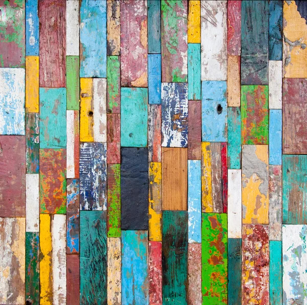 Colorful weathered wooden planks arranged vertically in turquoise, yellow, pink, and orange with peeling paint texture