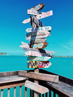 Colorful directional signpost on a wooden deck over turquoise ocean water