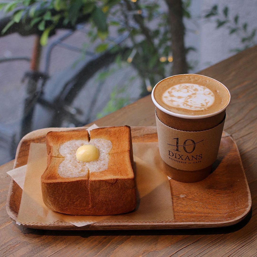 Toast with butter and a cup of latte on a wooden tray