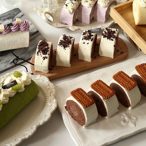 Variety of cream cake slices and rolls on plates and wooden boards