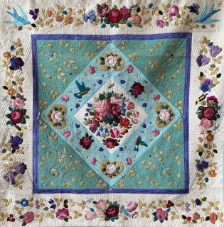 Turquoise and cream floral quilt with roses, birds, and decorative border in diamond pattern