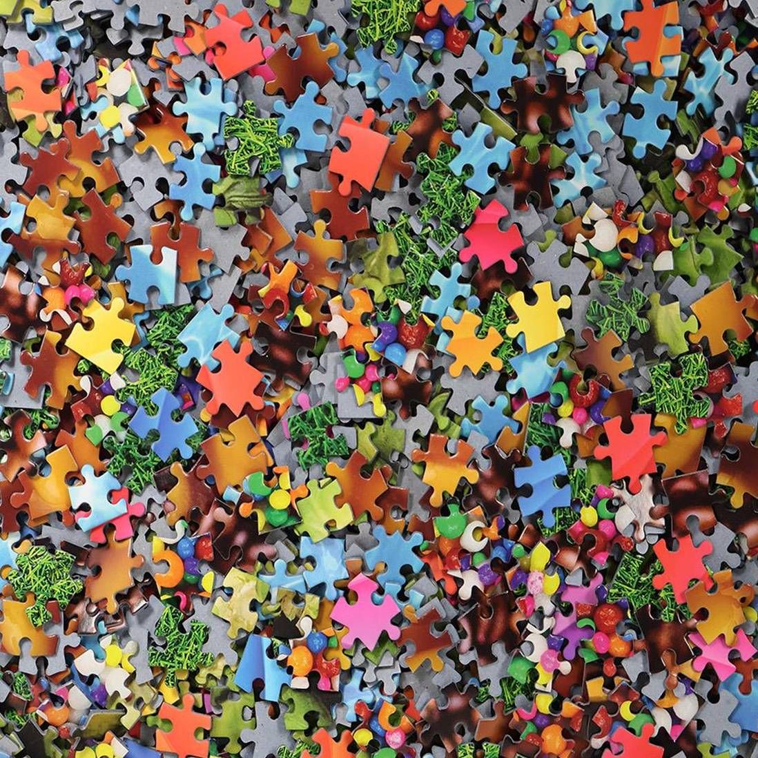 Close-up of many colorful jigsaw puzzle pieces scattered across the frame
