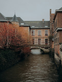 Narrow canal under a small stone bridge between old brick buildings