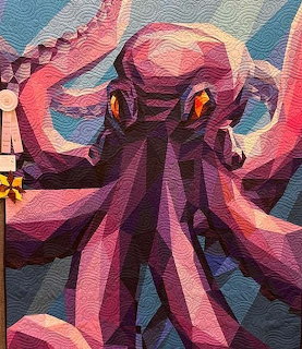 Colorful fabric quilt featuring a purple octopus with pink tentacles and yellow eyes on a blue-green quilted background