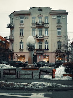 Historic building in Vilnius with large egg sculpture and snow-covered street in winter