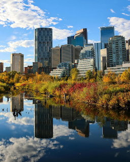 Calgary downtown skyline withyscrapers reflected in water surrounded by fall-colored trees