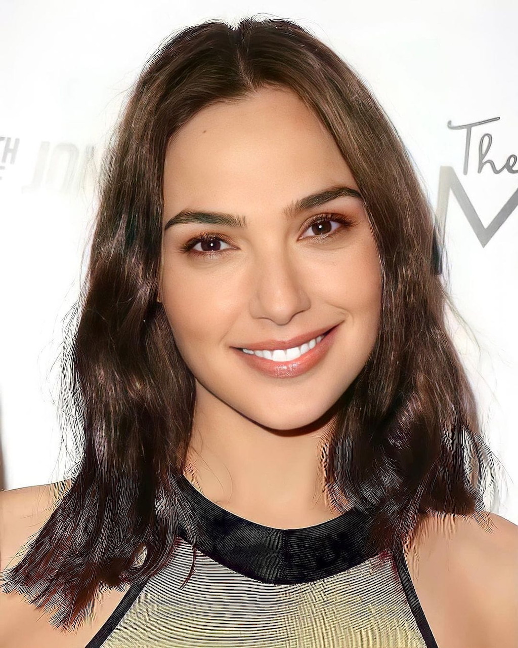 Smiling woman with brown wavy hair wearing a gray top at a media event