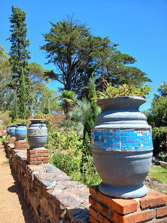 Blue decorative urns on a brick garden wall with trees and blue sky