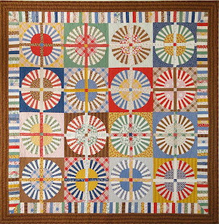 Colorful patchwork quilt with 16 circular wagon wheel pattern blocks in red, blue, yellow, green arranged in grid