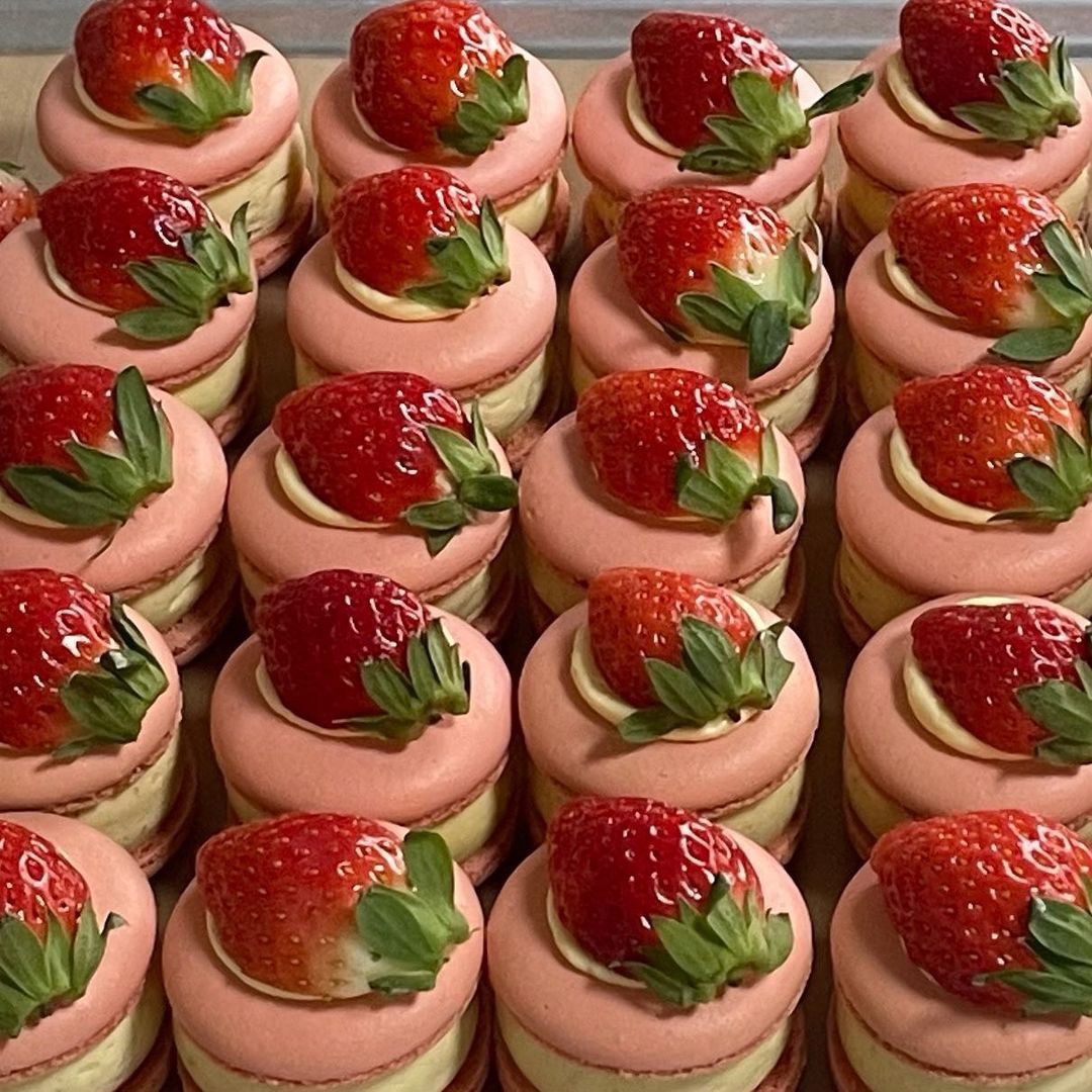 Close-up of pink pralines topped with fresh strawberries arranged in neat rows