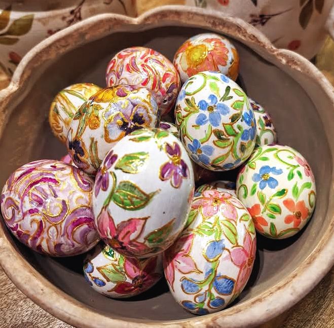 Colorful hand-painted Easter eggs with floral patterns in a wooden bowl