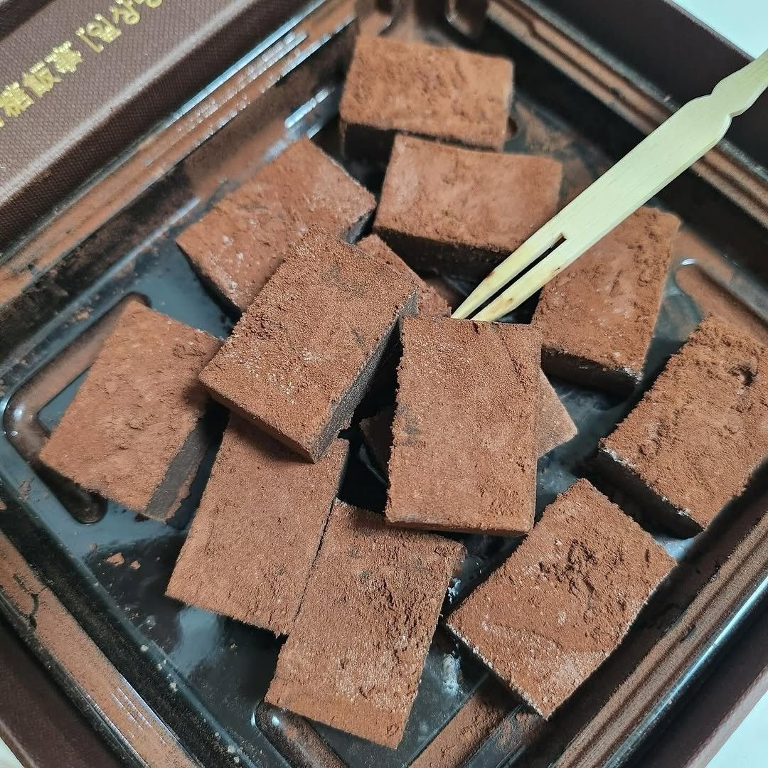 Square chocolate truffles dusted with cocoa powder on a dark plate