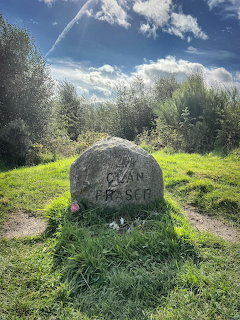 Clan Fraser carved stone in a grassy clearing with trees and blue sky