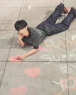 Young man lying on a tiled floor near pink chalk hearts and chalk writing