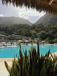 Turquoise resort pool with tropical plants and misty mountains in the background