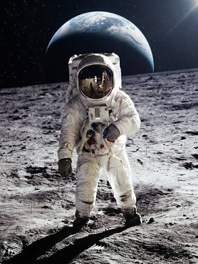Astronaut standing on the rocky Moon with Earth visible in the starry sky behind.