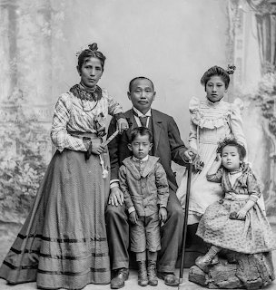 Black and white 1891 portrait of five-person Peruvian family in Victorian-era formal attire