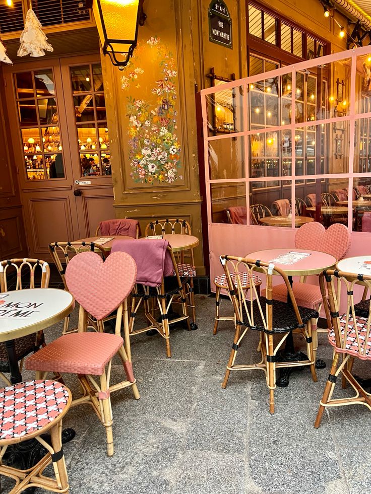 Parisian café terrace with pink heart-shaped chairs and bistro tables under warm golden lighting
