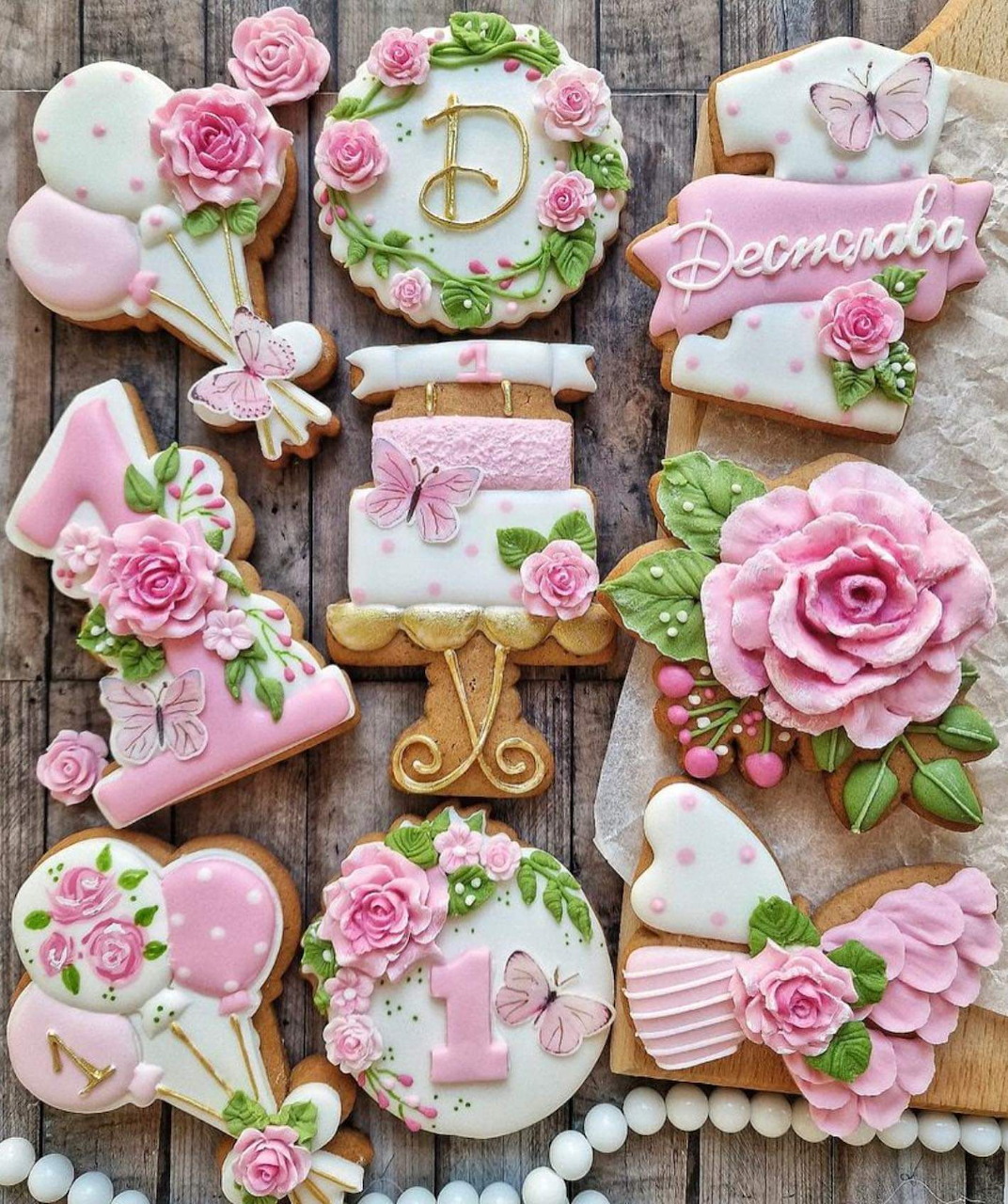 Assortment of pink floral decorated birthday sugar cookies with roses, butterflies, and number 1 designs