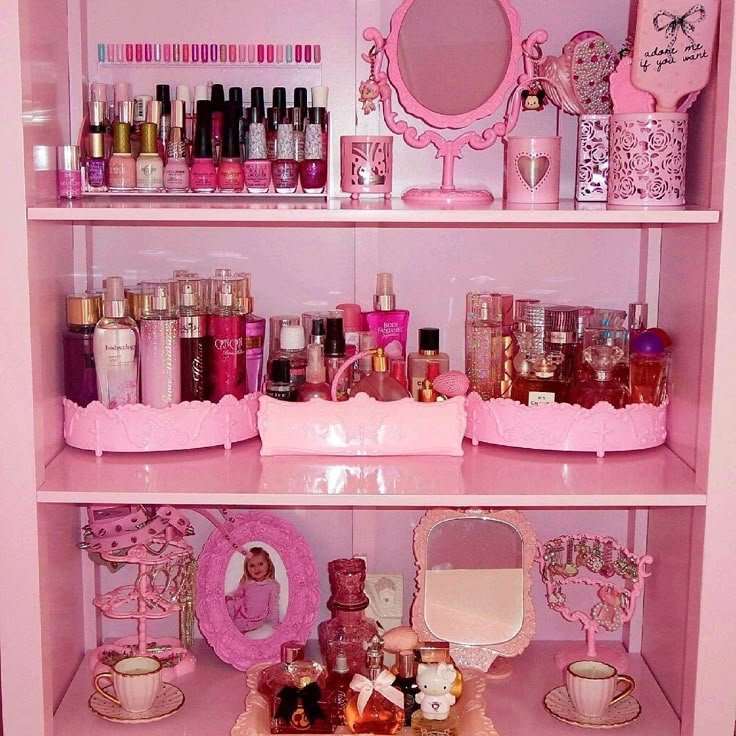 Pink vanity shelf with nail polish, perfume bottles, mirrors, teacups, and decorative accessories