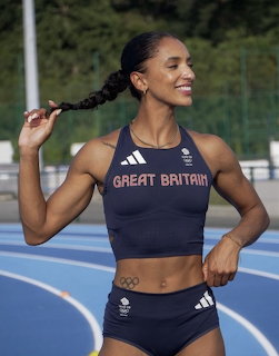 Smiling female athlete in navy sports top and shorts on outdoor track