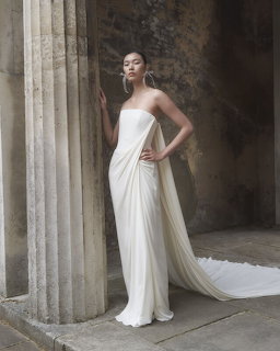 Bride in white strapless gown with long cape between stone columns