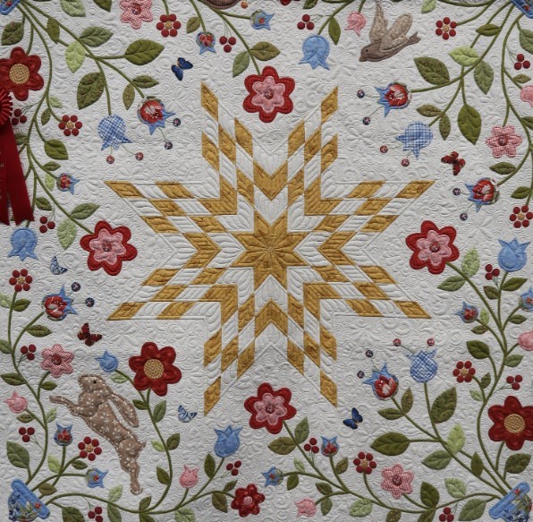 Quilted textile with yellow star center and floral border on white fabric