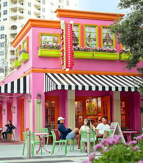 Bright pink ice cream shop with striped awnings and outdoor tables