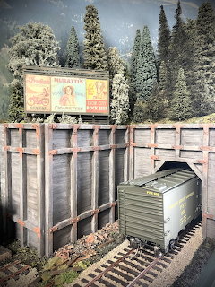 Model train freight car on wooden trestle bridge in miniature winter forest scene