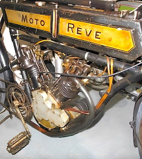 Close-up of a Moto Reve vintage motorcycle engine with exposed cylinder and chain drive