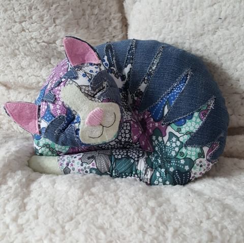 Colorful patchwork fabric cat pillow with button detail on textured background